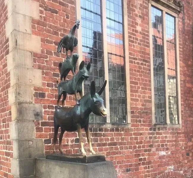 Die Bronzeskulptur der Bremer Stadtmusikanten vor der Backsteinwand des Rathauses