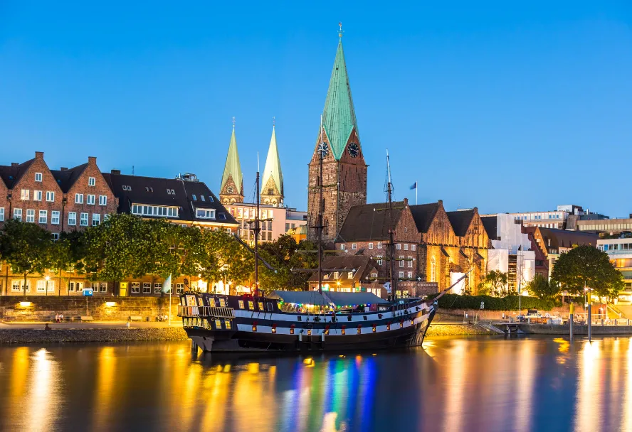 Die Schlachte am Abend, ein historischer Segler am Kai und die Domtürme dahinter