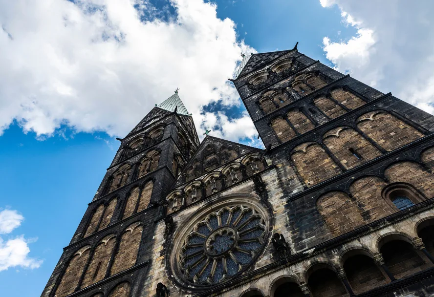 Der Bremer Dom St. Petri von unten, die beiden Türme und die Fensterrose vor Wolkenhimmel