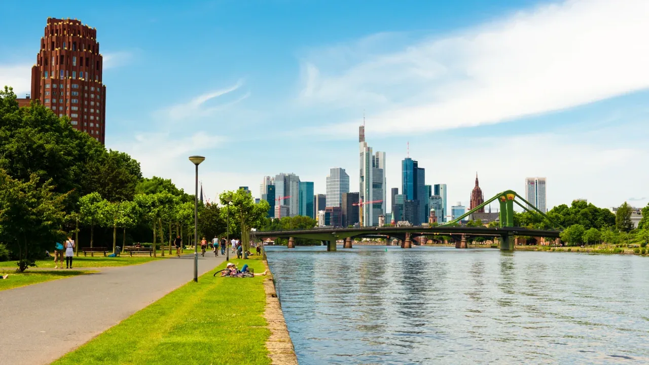 Der Mainuferweg unter Bäumen, gegenüber die Skyline