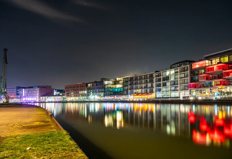 Der Münsteraner Stadthafen bei Nacht, die bunten Fassaden spiegeln sich im Wasser
