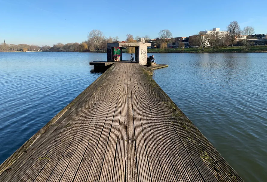 Ein hölzerner Steg führt über den Aasee, am Ende eine kleine Anlegestelle